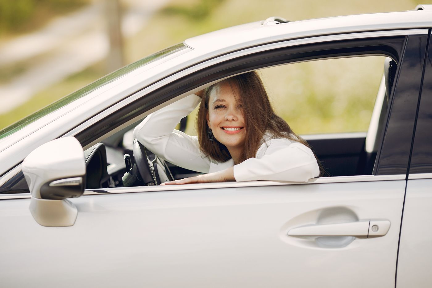 Cliente souriante au volant d'une voiture de location